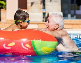 boy and grandfather in home swimming pool