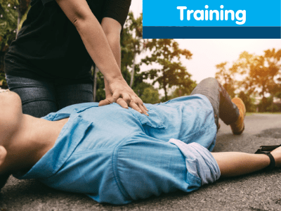 A person performing CPR on a man who has collapsed on a road