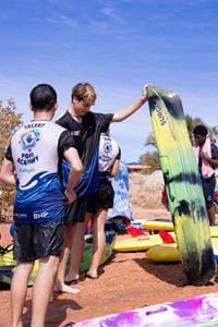 Talent Pool Academy participants stand on the river shore with kayaks