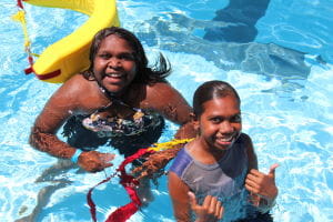 Two Aboriginal children in the pool with a rescue tube