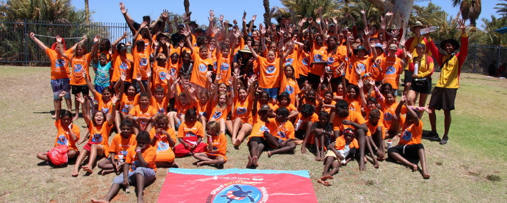 Kids gather on the grass at South Hedland Aquatic Centre wearing Spirit Carnival t-shirts