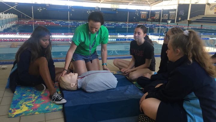Four girls from Geraldton girls academy with an instructor demonstrating on a CPR manikin by the pool