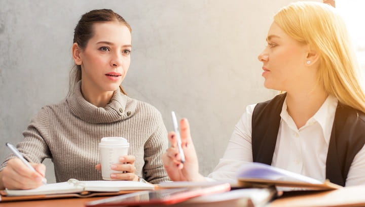 two women having a discussion at a meeting table