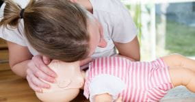 A mother demonstrating CPR on an infant