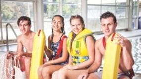 Four young persons at the swimming pool with lifesaving equipment