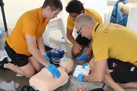group of lifeguards practising CPR on a manikin