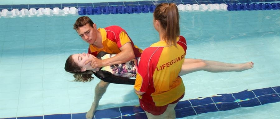 Two lifeguards in the pool with an unconscious lady 