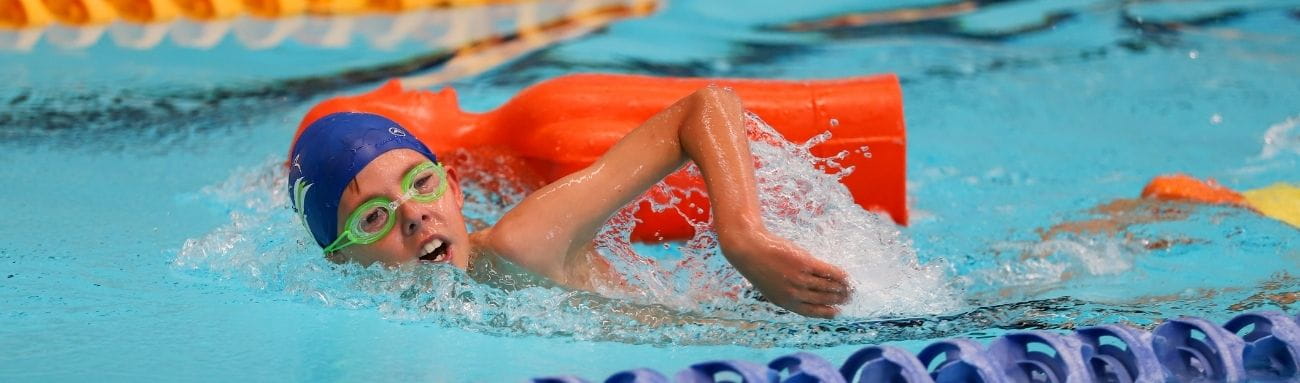 Child swimming while towing orange manikin