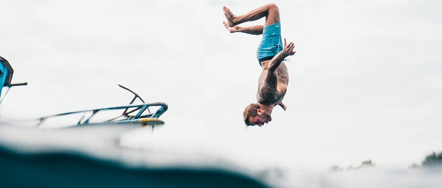 man doing a backflip off a boat into the water