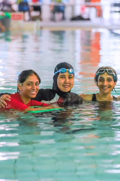 Adult students stand in the water and smile at the camera