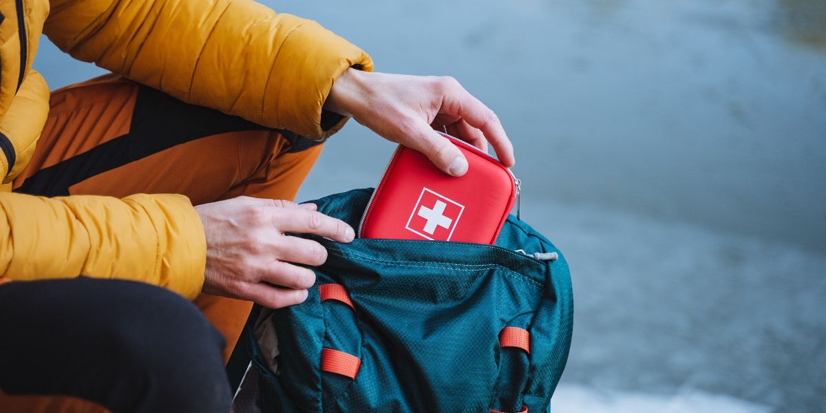 First aid kit being pulled from backpack by person wearing winter clothes