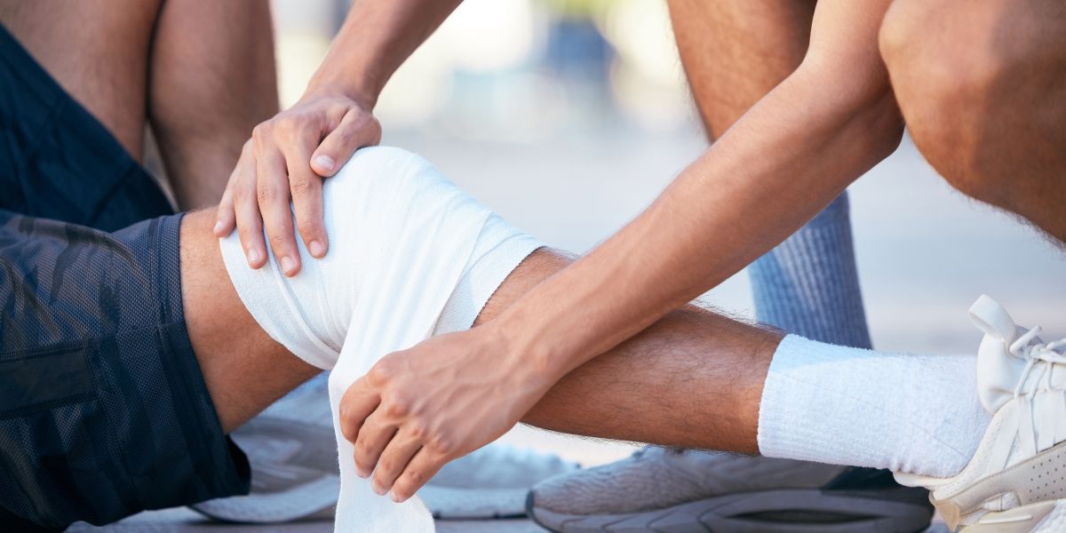 Person lying on sport track with knee being bandaged