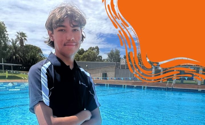Teenage boy in a Royal Life Saving shirt smiling confidently with outdoor pool in the background.