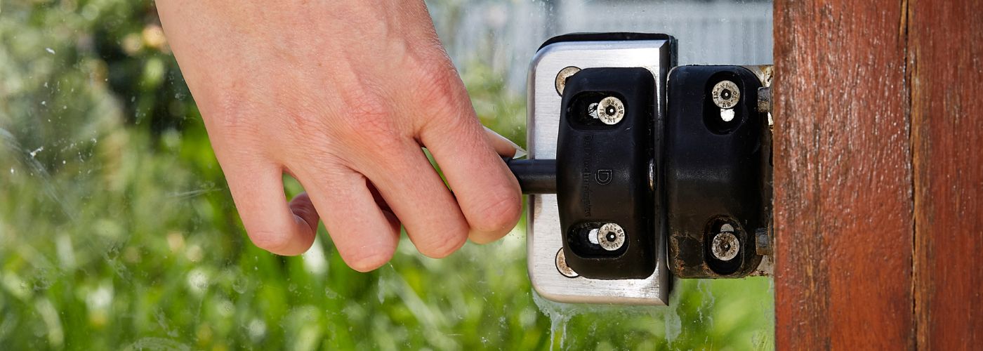 Close up photo of a hand unlocking a pool barrier gate