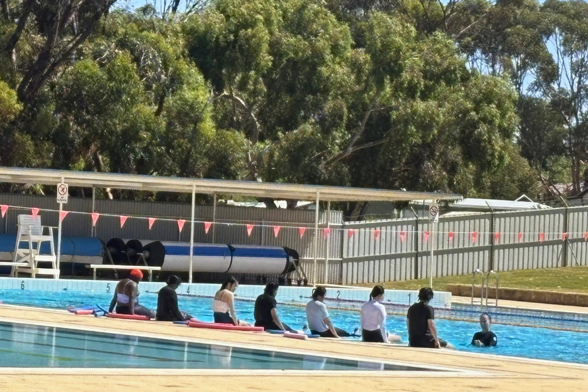 Distant shot of participants sitting along the edge of the pool