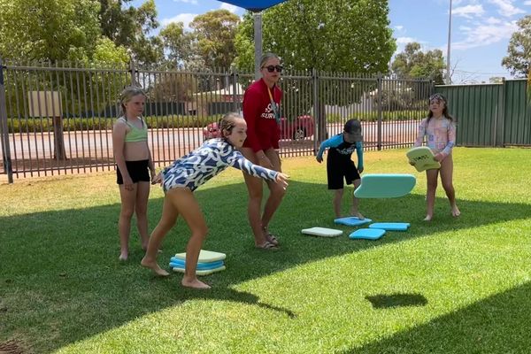 Students standing on grass throwing kickboards