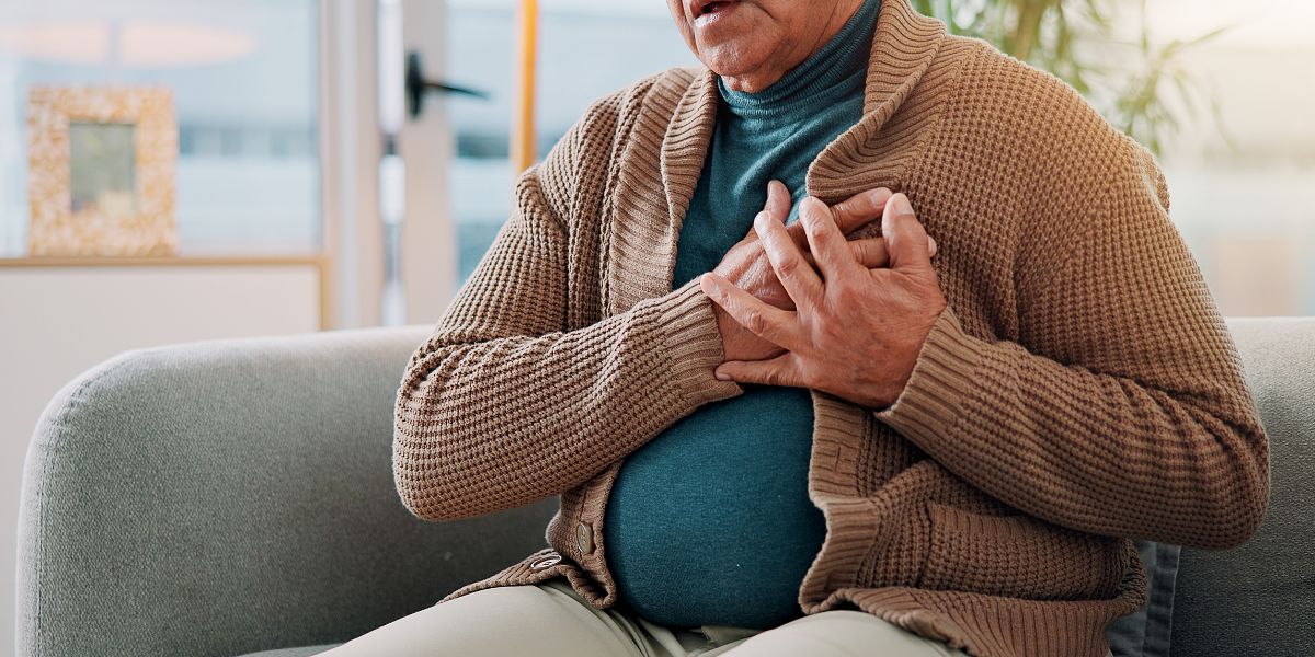Elderly man clutching his chest sitting down