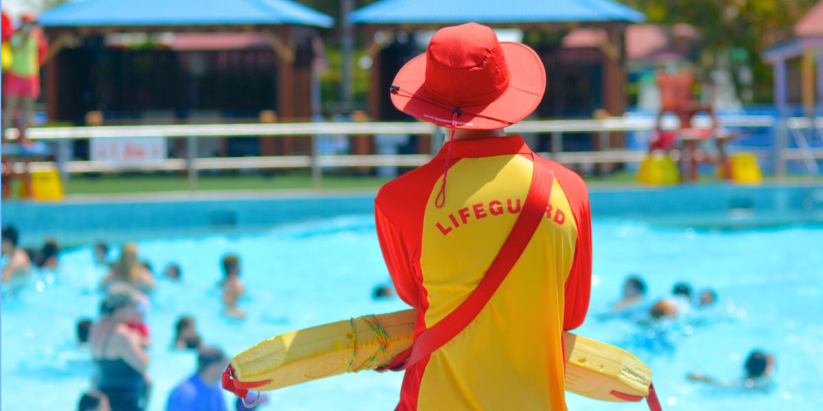 Lifeguard standing looking out at pool with back to camera
