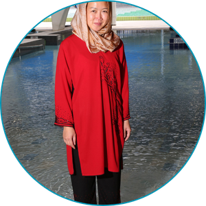 woman wearing full length tunic and pants and hijab, standing ankle-deep in shallow pool