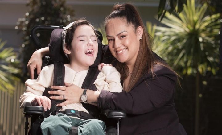 Mother Simone sitting on the left hand side of her teenage son Ari who is in a wheelchair. Both are smiling