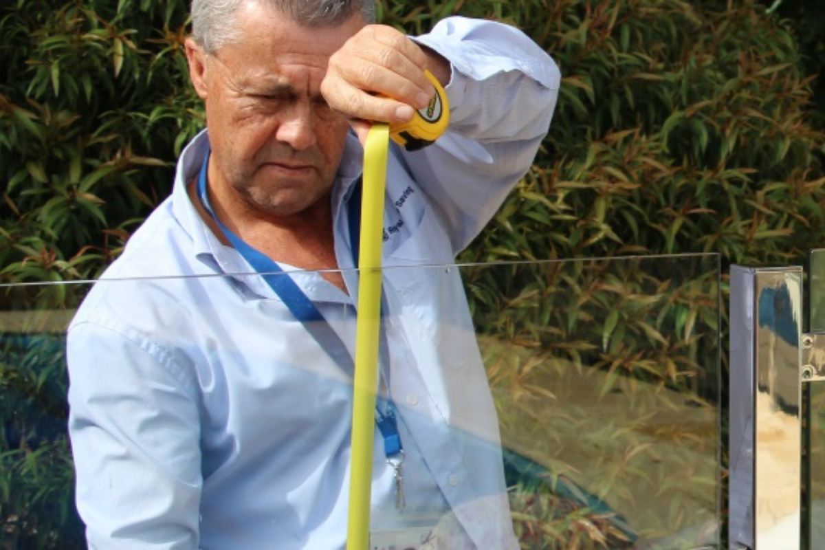 A Royal Life Saving WA Inspector measuring a home pool barrier