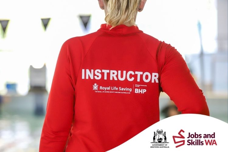 Royal Life Saving swimming instructor in a red uniform standing beside an indoor swimming pool