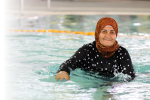 Older woman smiles at camera while standing in pool