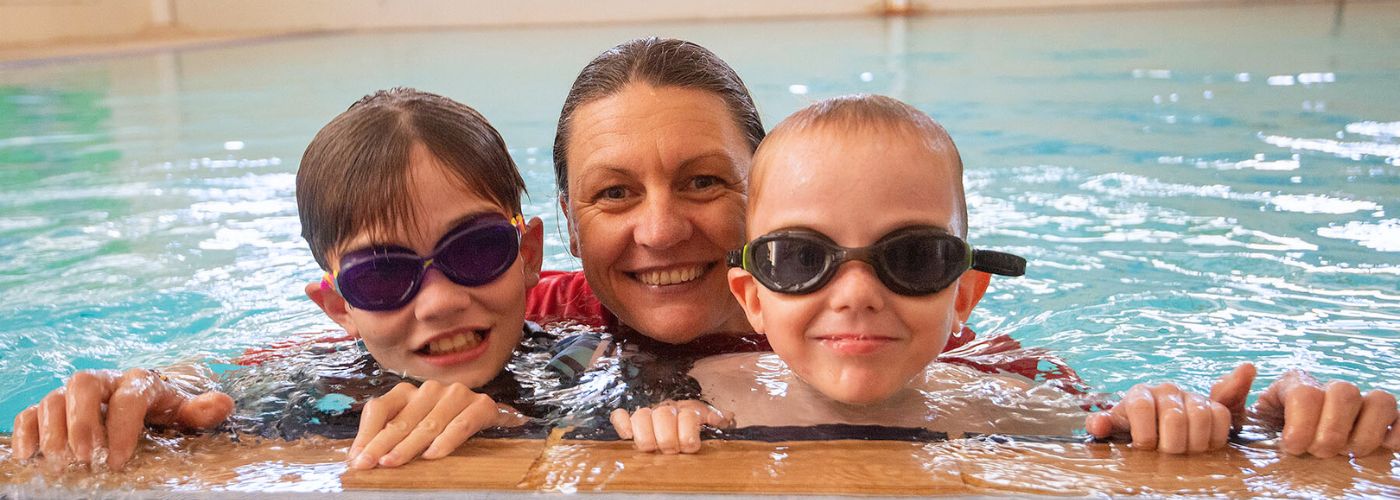 Teacher smiling at camera with two young students