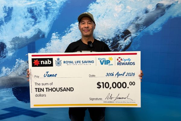 Man standing with giant cheque in front of blue wall