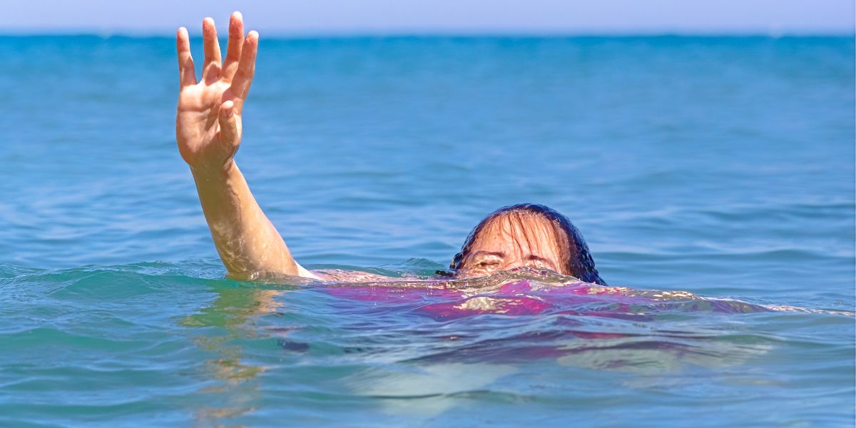Woman with water up to head reaching hand out of water