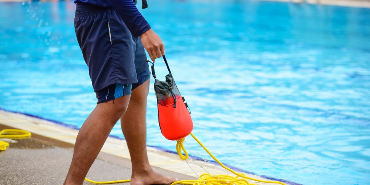 Man holding throwbag on edge of pool