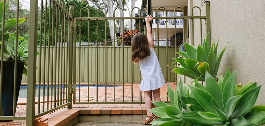 little girl trying to open pool fence