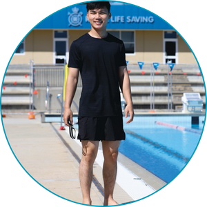 man wearing swim shorts and short sleeve shirt standing next to a pool