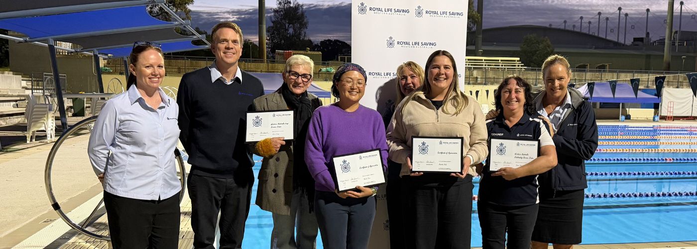 Group photo of award recipients and staff in front of pool