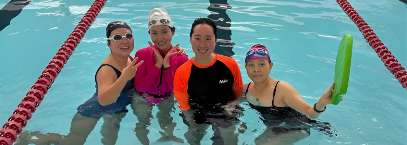 Teacher standing with students in pool smiling
