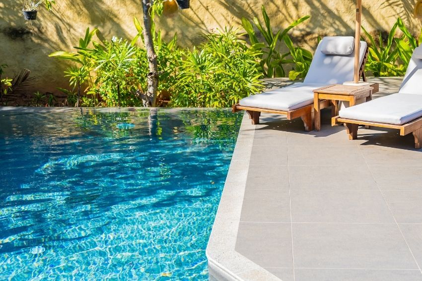 Small in ground pool with two sunchairs next to the pool on the concrete