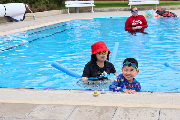 A young boy and his mum at the edge of the pool