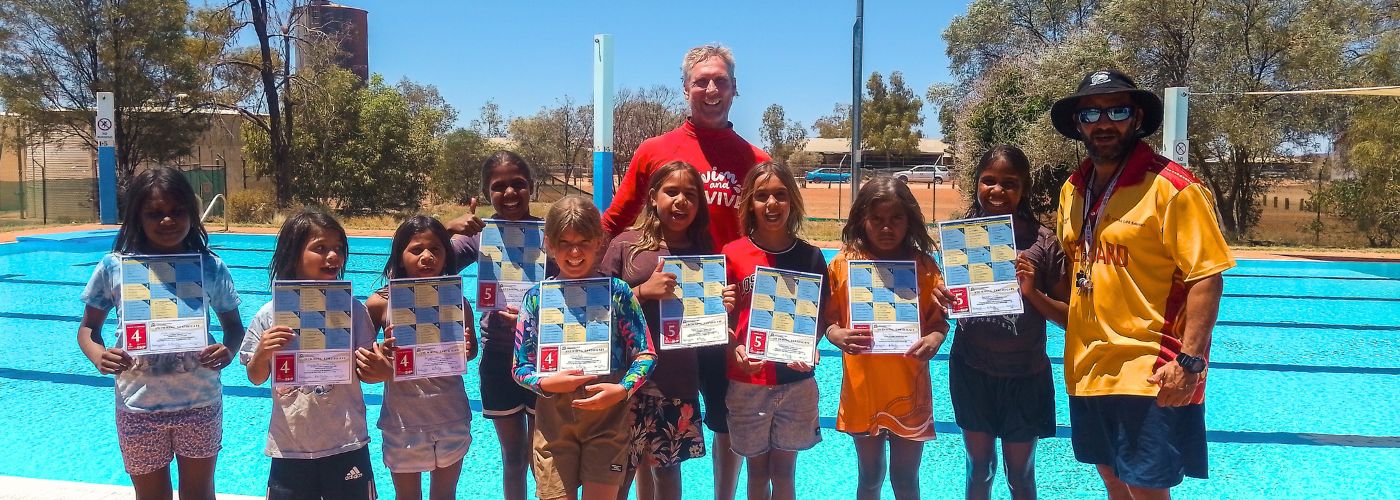 Photo of children posing with swimming certificates and their instructor