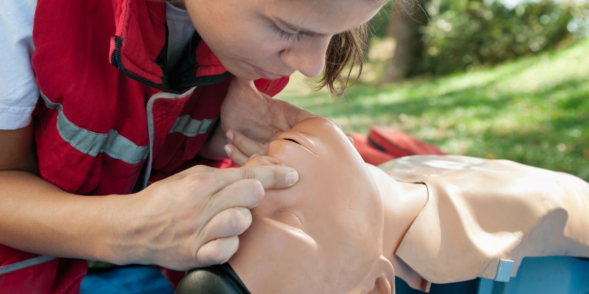 Woman leaning over for mouth-to-mouth on mannequin