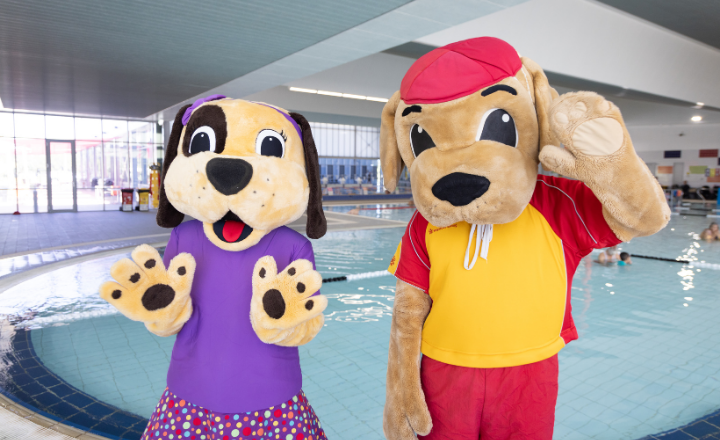 Walter and Wendy plush mascots standing next to indoor pool