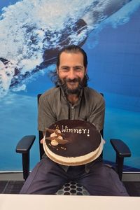 Marcus holding a cake reading "winner"