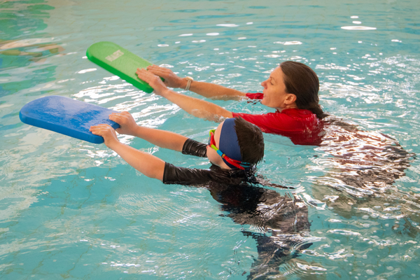 A SAIL participant and his instructor swim with kickboards