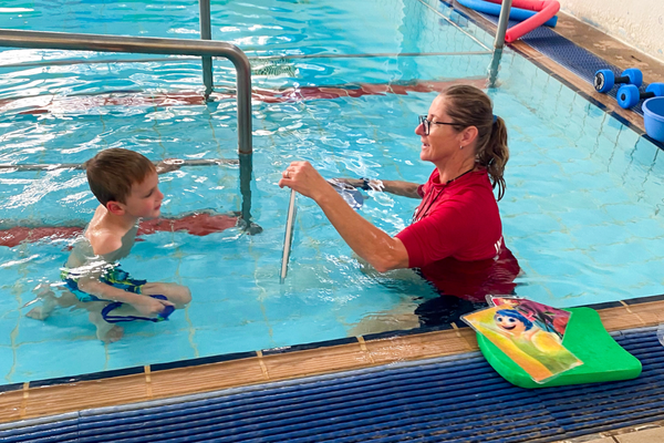 A SAIL participant watches his instructor demonstrate something in the pool