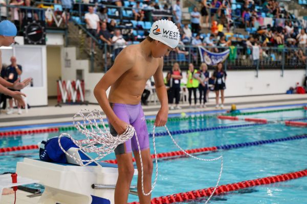 A West Life Saving competitor prepares a rope on the starting block before a pool lifesaving event.