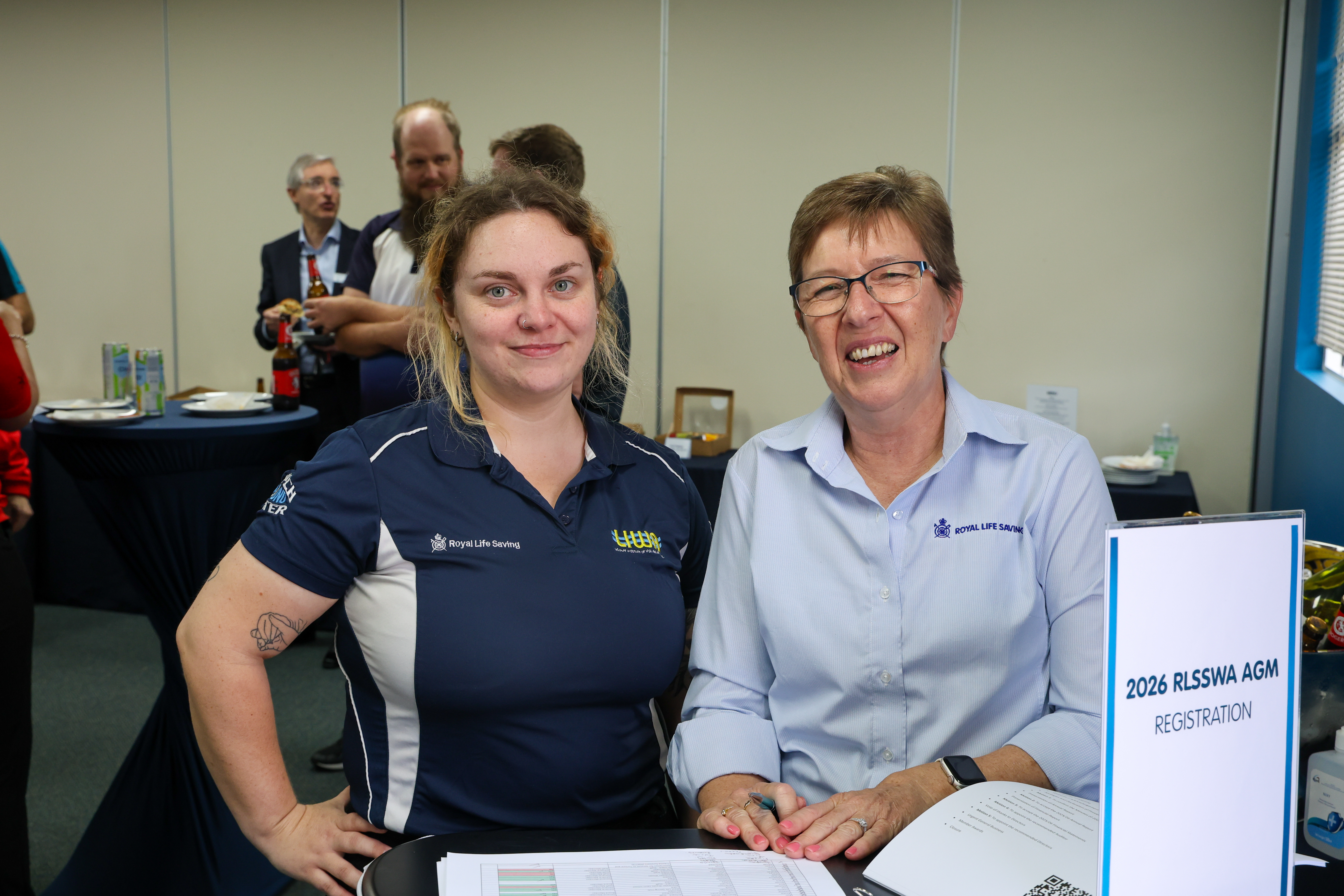 Two women smile beside the registration table at Royal Life Saving WA&rsquo;s 2026 AGM.