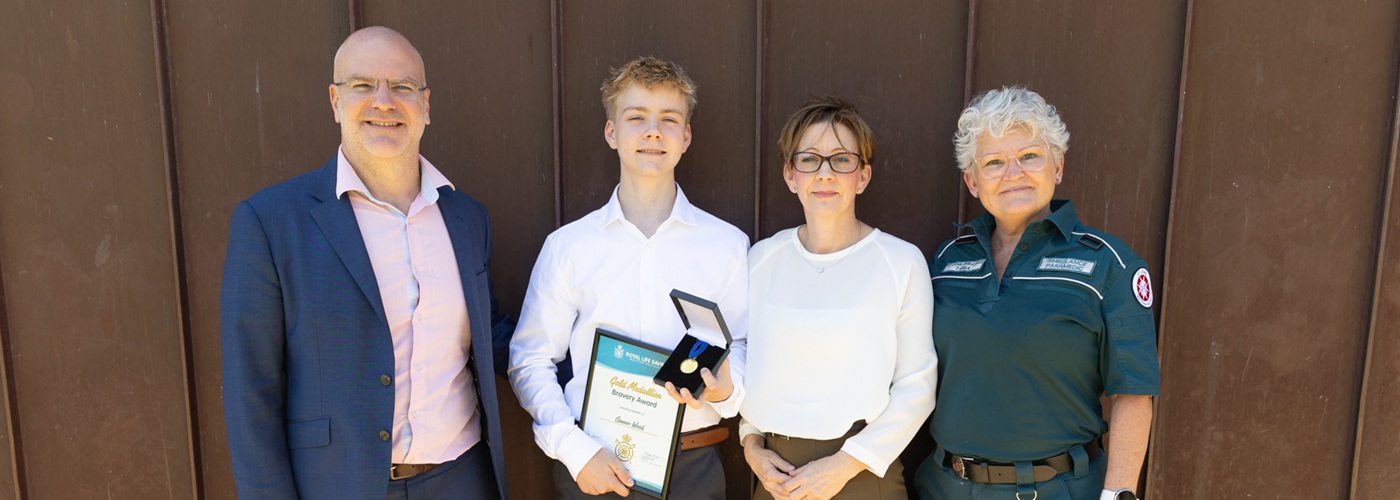 Connor Wood holding his Bravery Award next to family