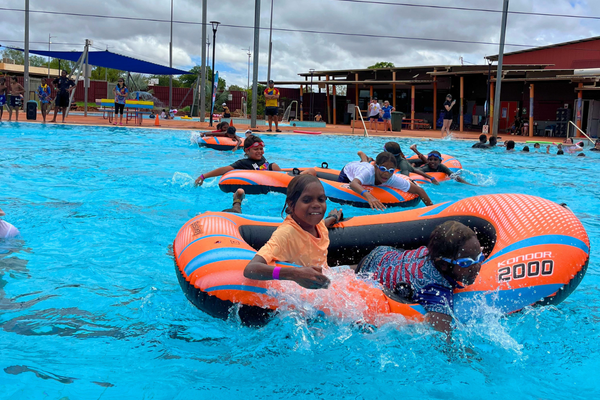 Kids race inflatable rafts in the pool