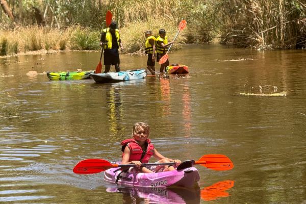Kids in kayaks smiling at camera