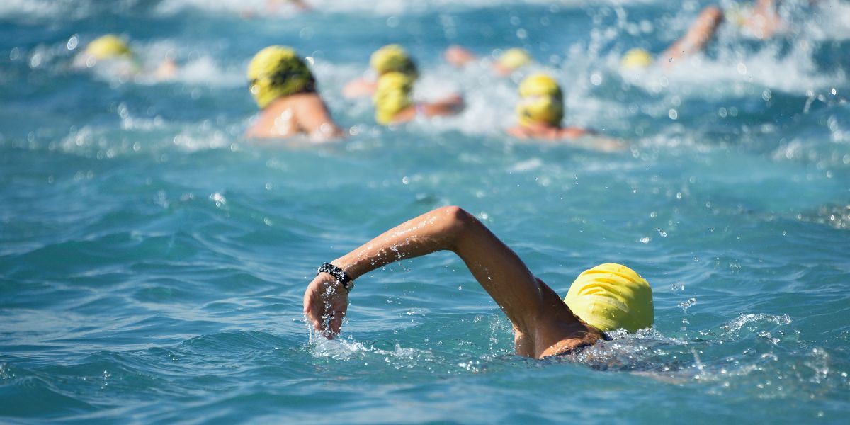 Triathlon swimmers wearing yellow caps swimming in open water