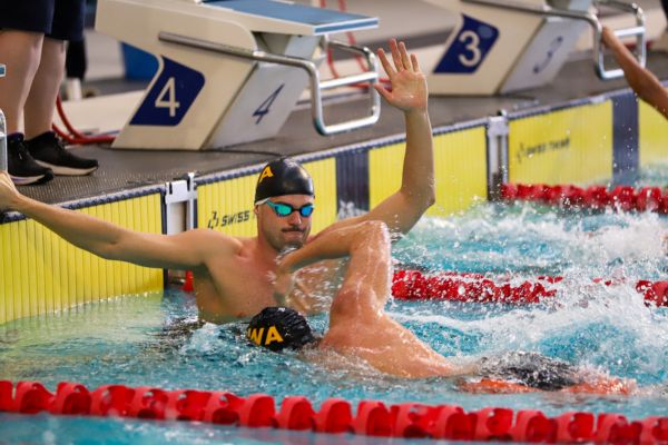 Two Western Australian competitors complete a relay exchange at the end of the pool.